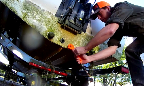 Man using boat decontamination station to clean boat trailer to stop the spread of aquatic invasive species. 